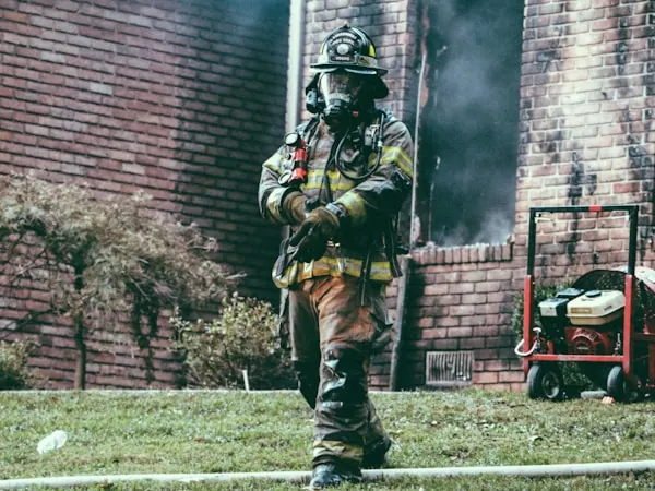 Bombero con máscara facial y equipo autónomo avanzando en escena