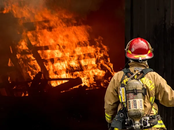Bombero con traje estructural completo frente a un incendio