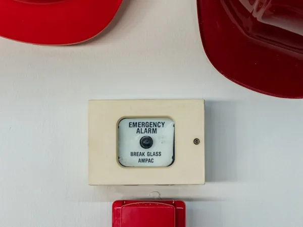 Estación manual de alarma con tapa de vidrio junto a cascos de brigada