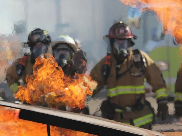 Bomberos con equipo de respiración autónoma frente a un frente de fuego