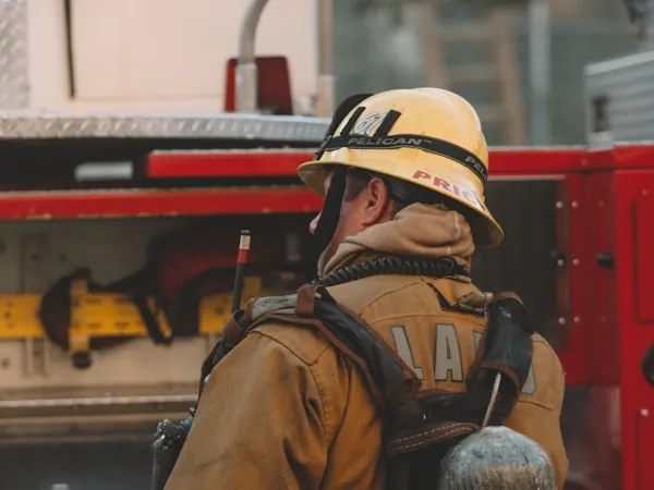 Bombero equipado junto a la unidad en escena