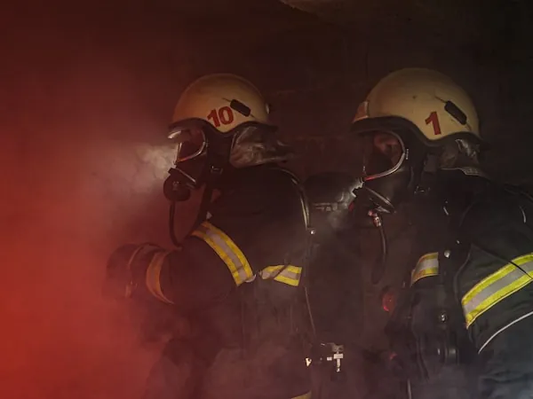 Bomberos con máscara facial completa operando en ambiente con humo