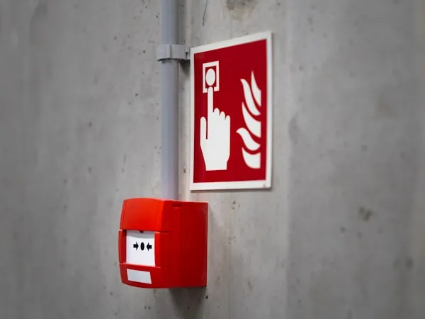 Señal de activación de alarma junto a estación manual roja en muro