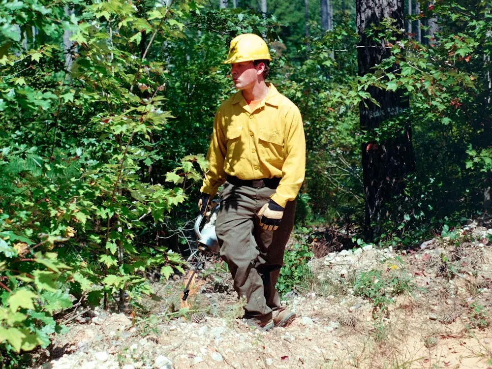 Brigadista forestal equipado con ropa aramídica y casco en zona boscosa