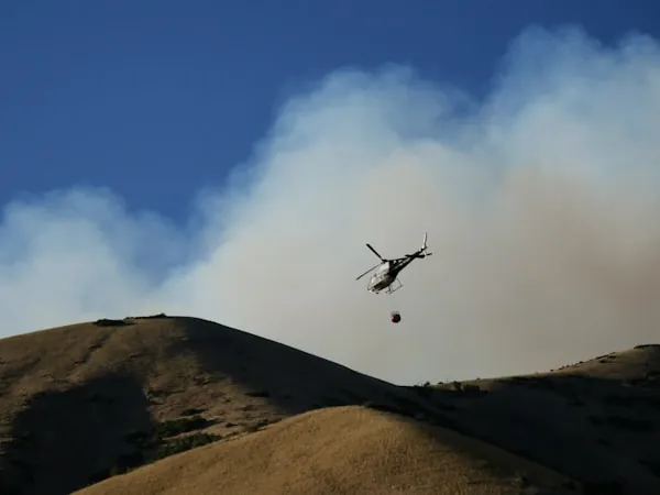 Helicóptero descargando agua sobre un incendio en ladera
